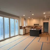 Unfinished kitchen with cabinets, island, and large glass doors. 