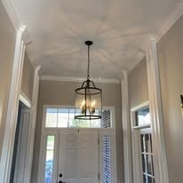 An entryway with a hanging lantern; a door with a window and white molding.