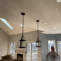 Two pendant lights hanging from a ceiling, a person in a room.