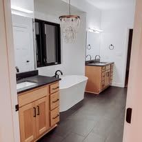 Bathroom with a vanity, large mirror, black framed window, and a white soaking tub.