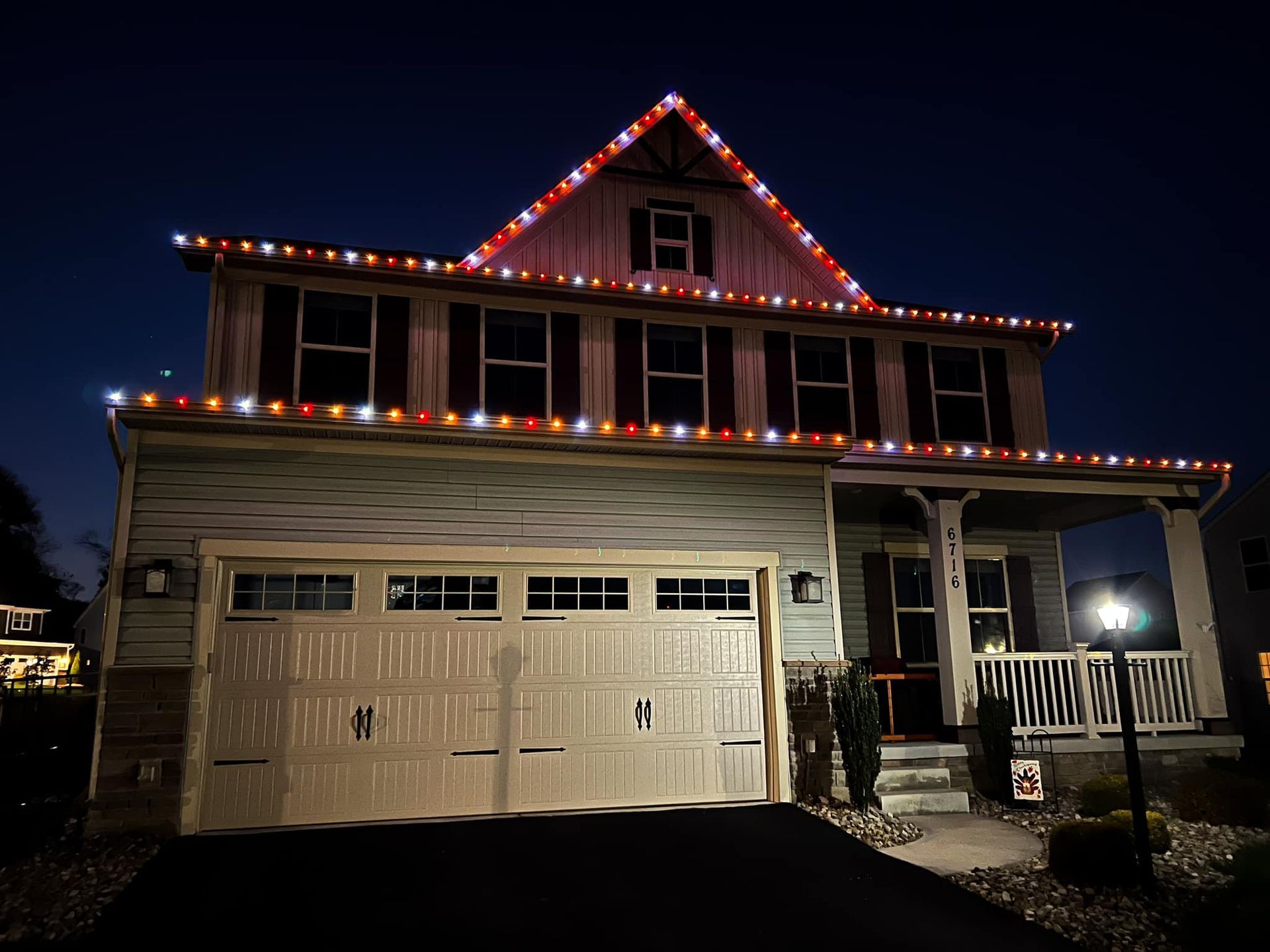 House at night decorated with red and white Christmas lights along the roof.