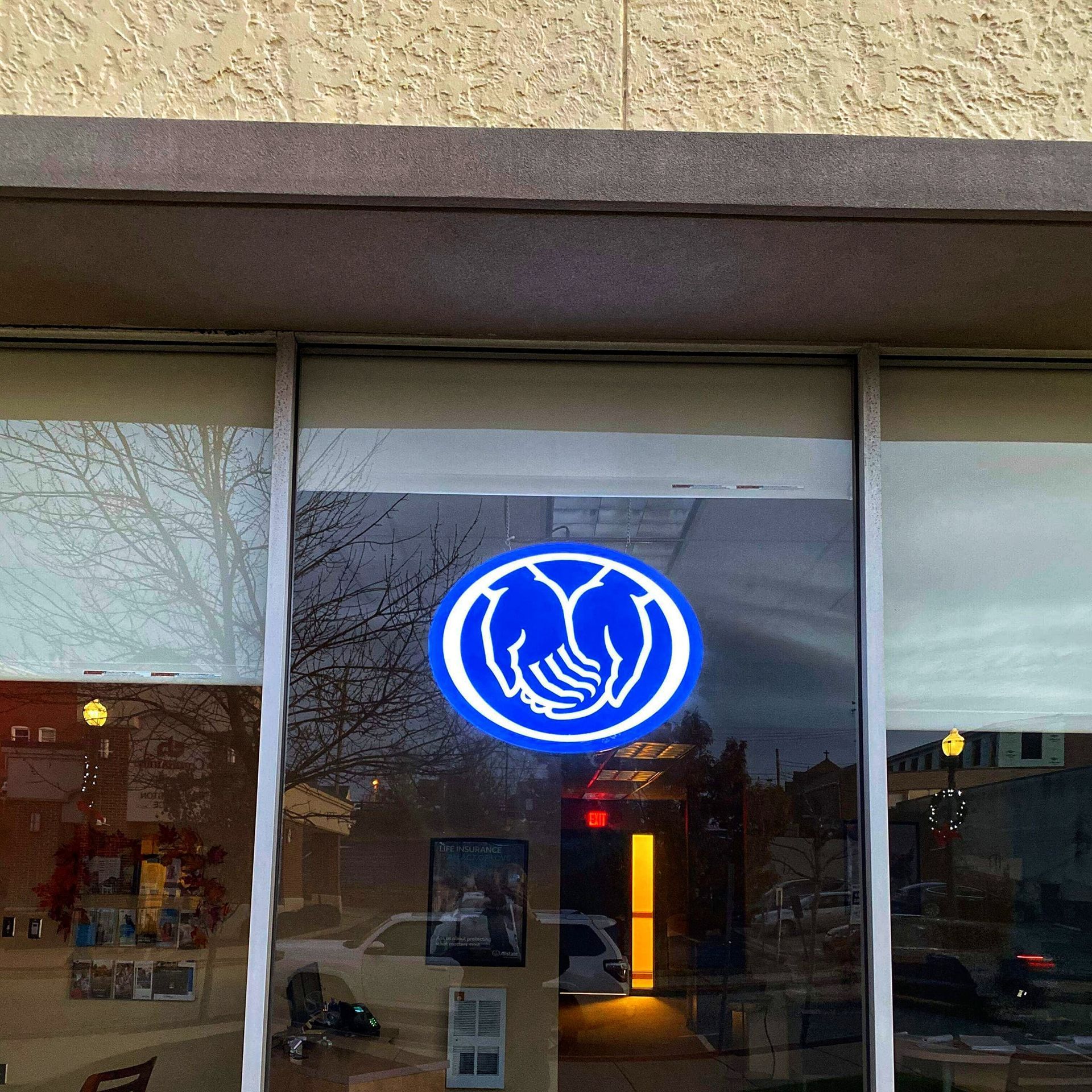 Blue cross logo with cupped hands in window. Building exterior with reflections.