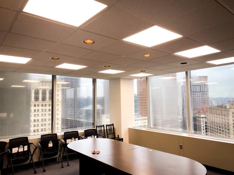Conference room with large windows, city view, and a table surrounded by chairs.