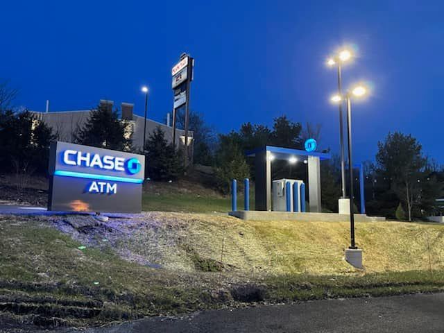 Chase ATM sign and drive-up ATM at dusk, illuminated with blue lights.