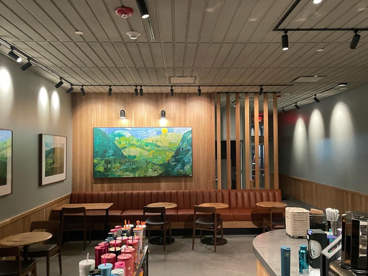 Interior of a Starbucks with wooden accents, artwork, and seating. 
