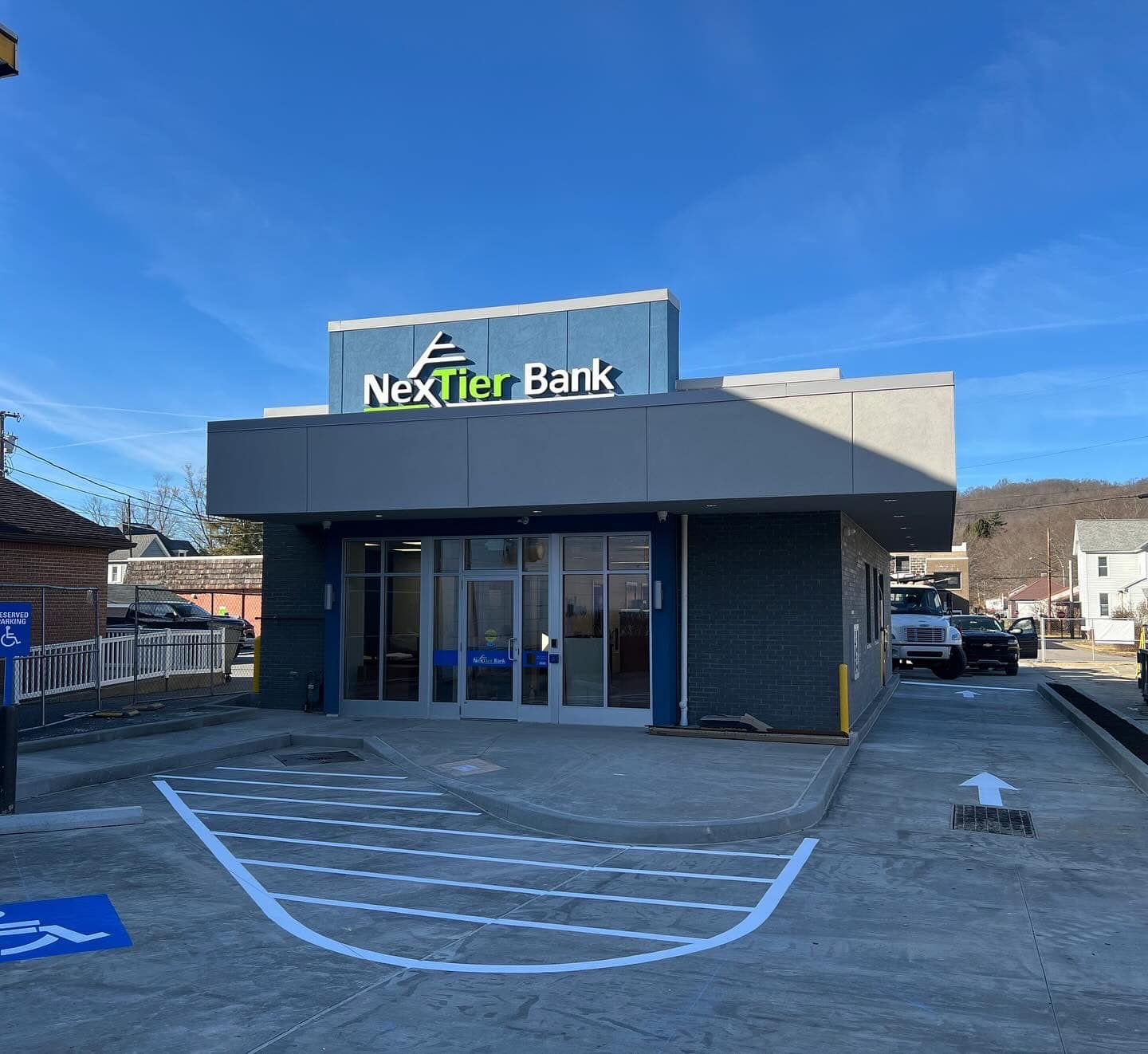 NexTier Bank building with drive-up lane. Gray and blue exterior, sunny day. 