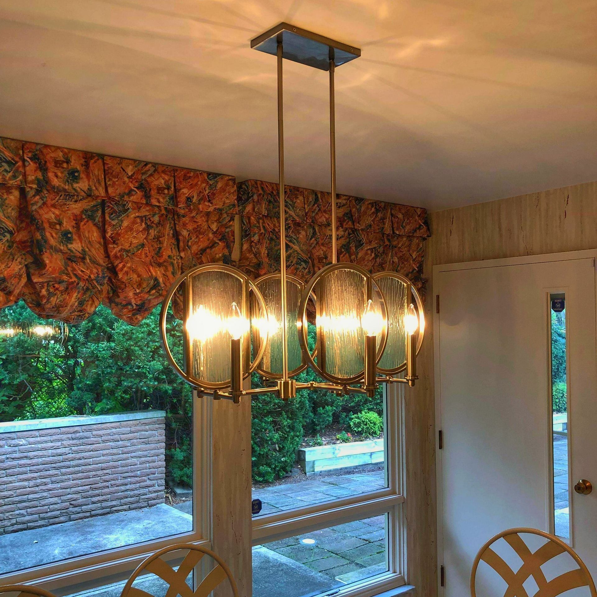 Chandelier with glass globes hanging above a dining table near a window.