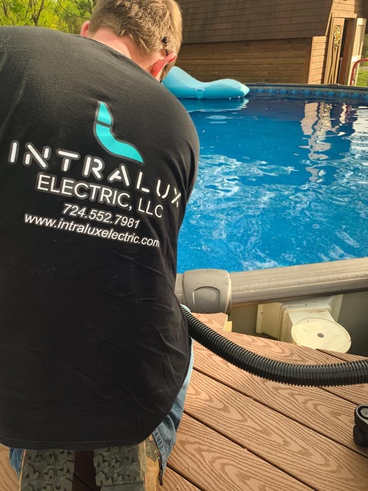 Man in Intralux Electric shirt working on pool equipment near a pool.