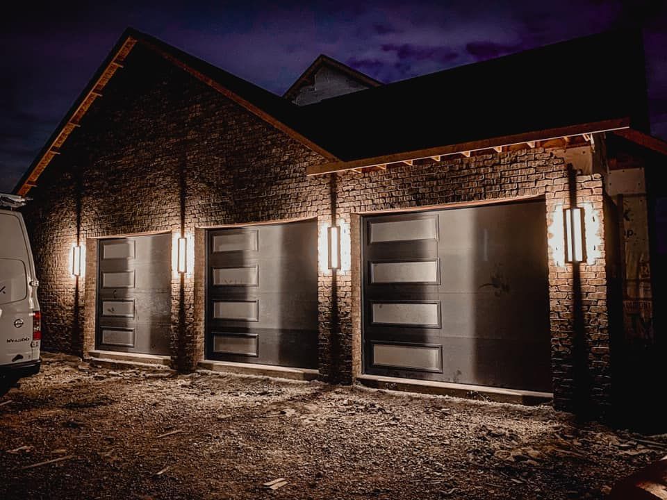A modern brick garage with three bays, each lit by vertical sconces. 