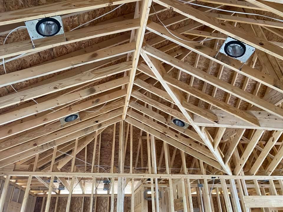 Unfinished wooden ceiling with recessed lighting installed.