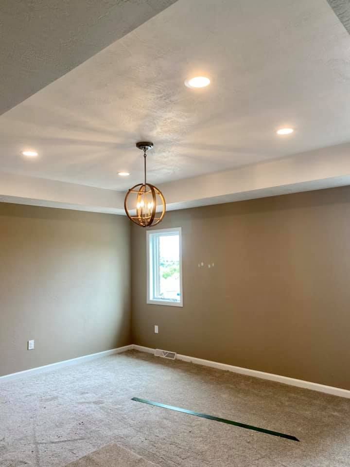 Empty room with tan walls, recessed lighting, and a globe chandelier.