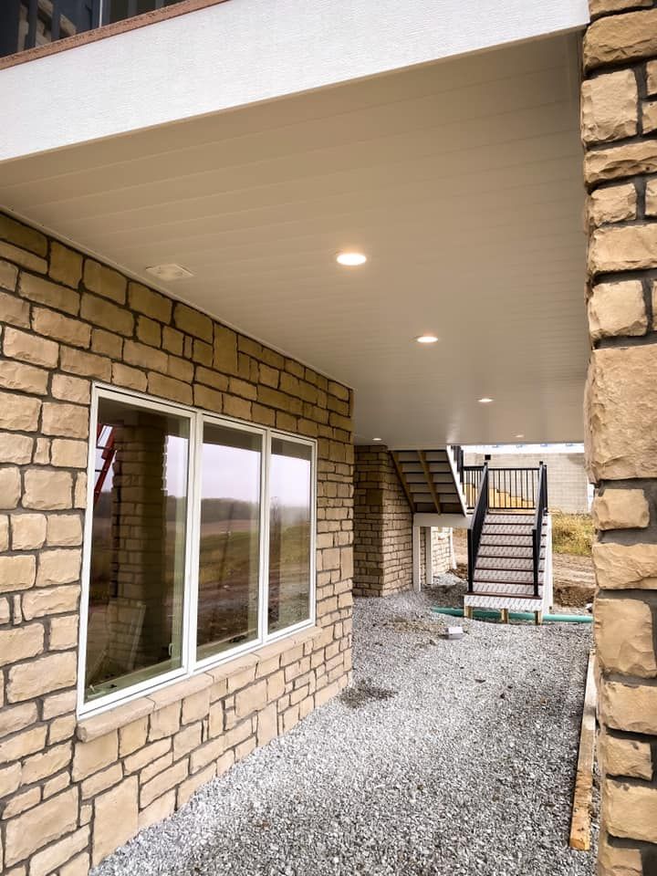 Exterior of building with stone walls, white trim, and a covered walkway. 