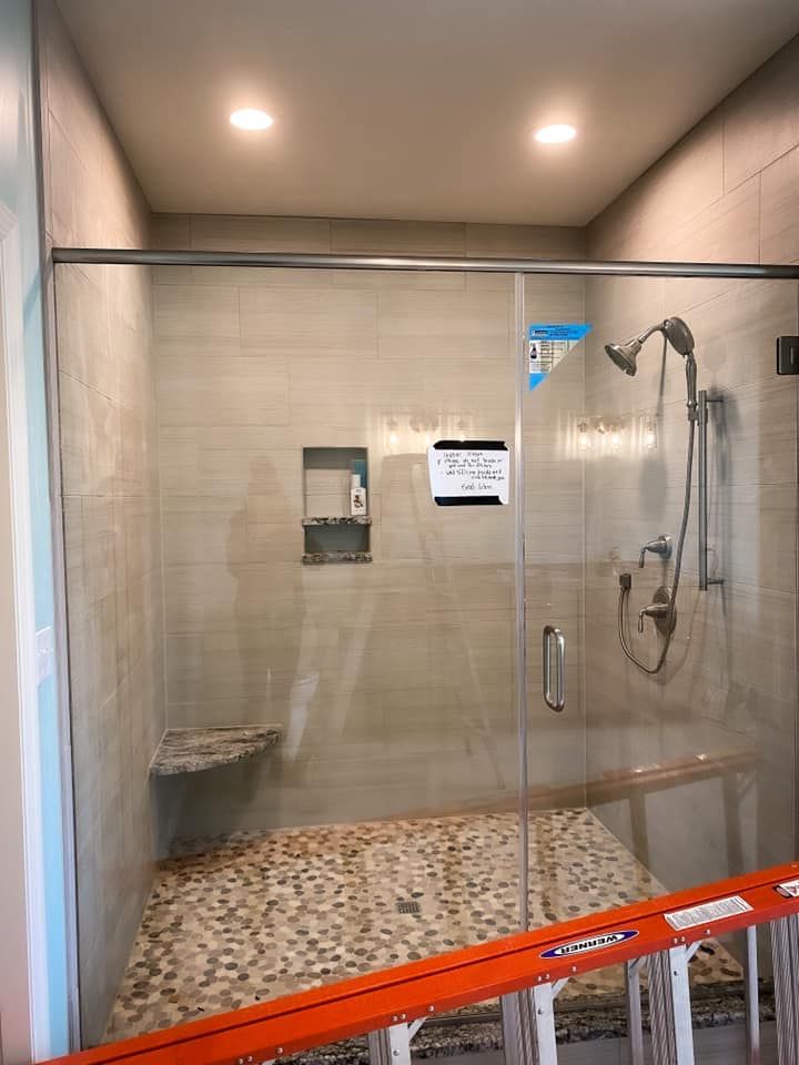 Shower with glass doors, stone tile floor, and built-in bench and niche. 