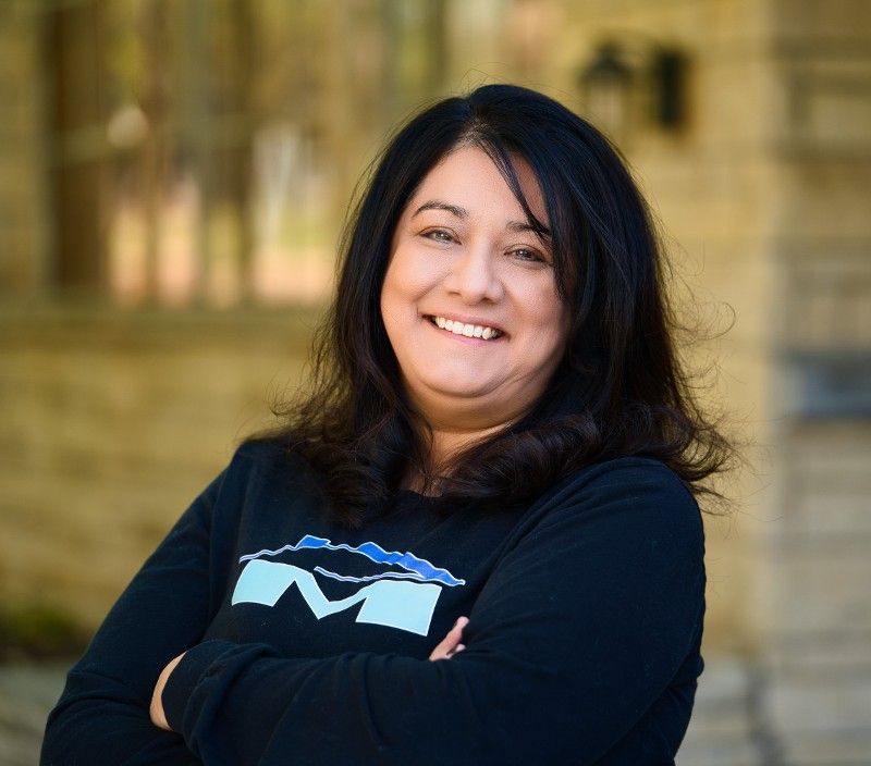 Claudia Stark wearing a black shirt with the letter m on it