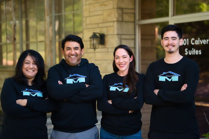 A group of people wearing Mendoza logo sweatshirts are posing for a picture in front of a building.