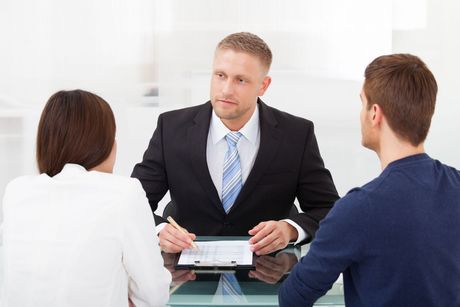 A man in a suit and tie is sitting at a table with two people.