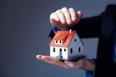 A person is holding a small model house in their hands