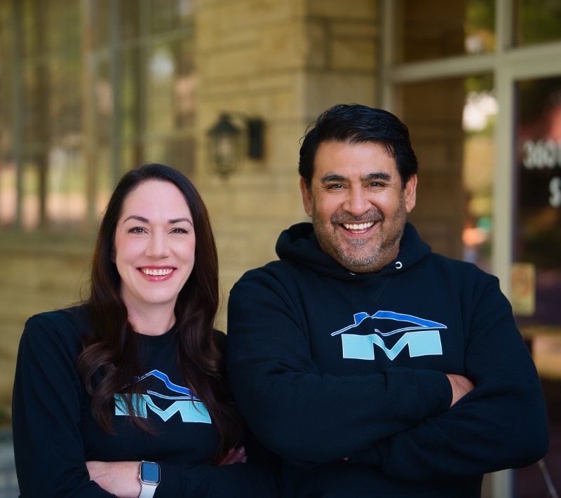 Katrina and Greg Mendoza posing for a picture with their arms crossed