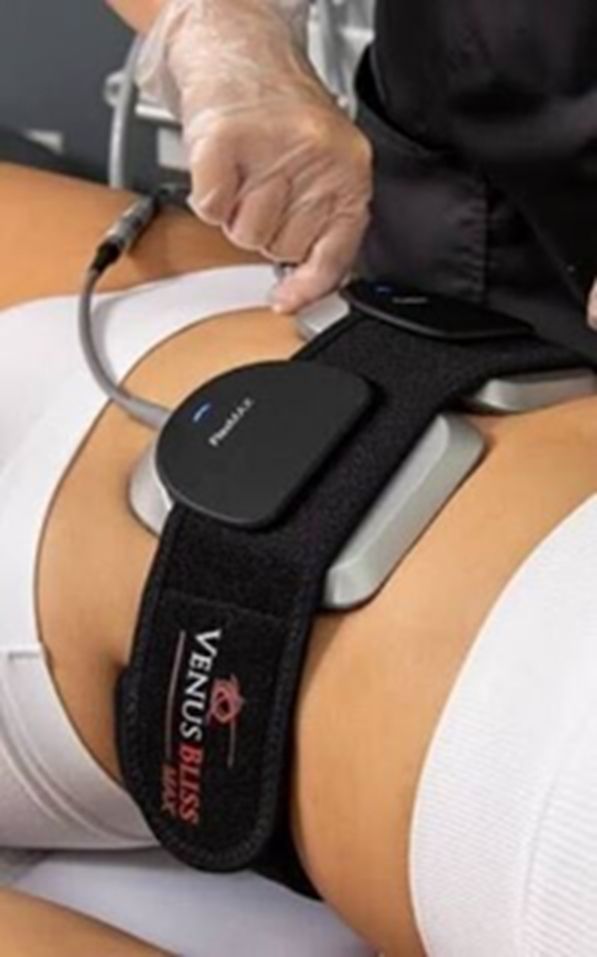 Person undergoing Venus Bliss treatment. Device with black strap and pad on abdomen; technician adjusting.