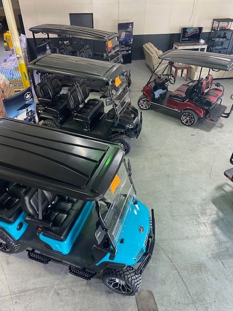 A bunch of golf carts are parked in a garage