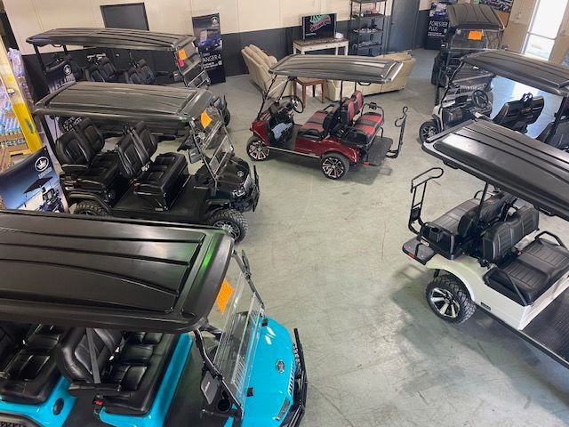 A bunch of golf carts are parked in a garage.