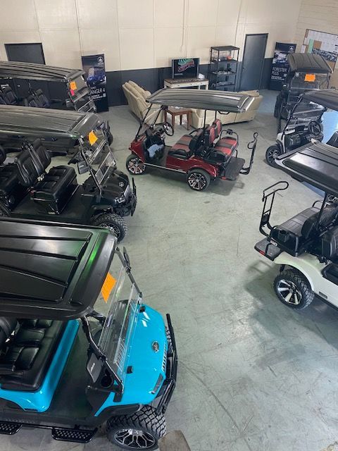 A bunch of golf carts are parked in a garage.