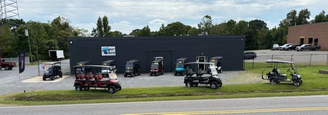 A bunch of golf carts are parked in front of a building.