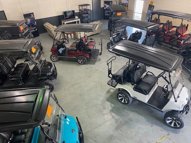 A bunch of golf carts are parked in a garage.