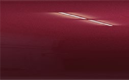 A close up of a red car door with a scratch on it.