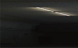 A light is shining through the ceiling of a dark room.