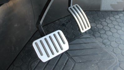 A close up of a car 's brake pedals on a black mat.