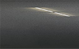 A close up of a gray wall with a light shining through it.