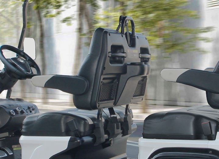 A golf cart with a bag hanging from the back seat.