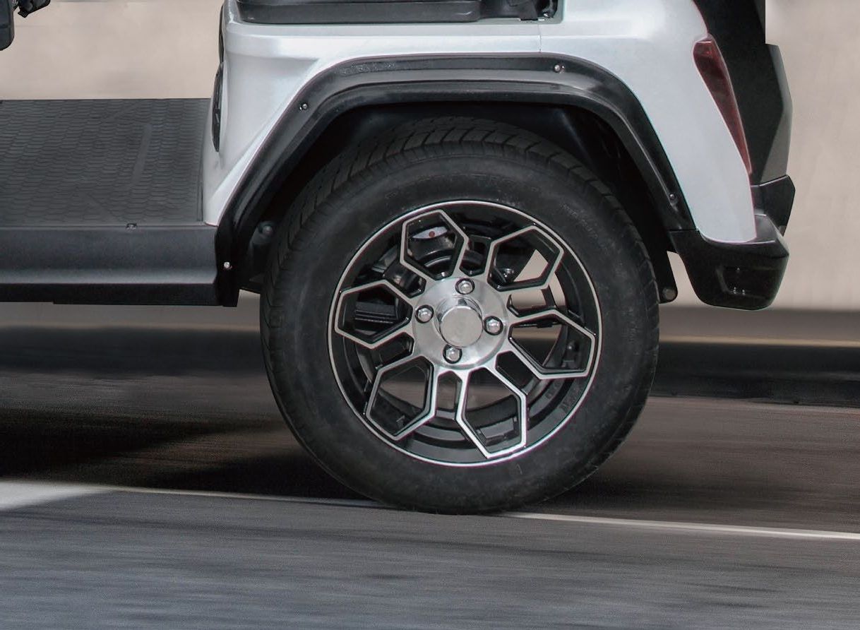 A close up of a golf cart wheel in a parking lot.
