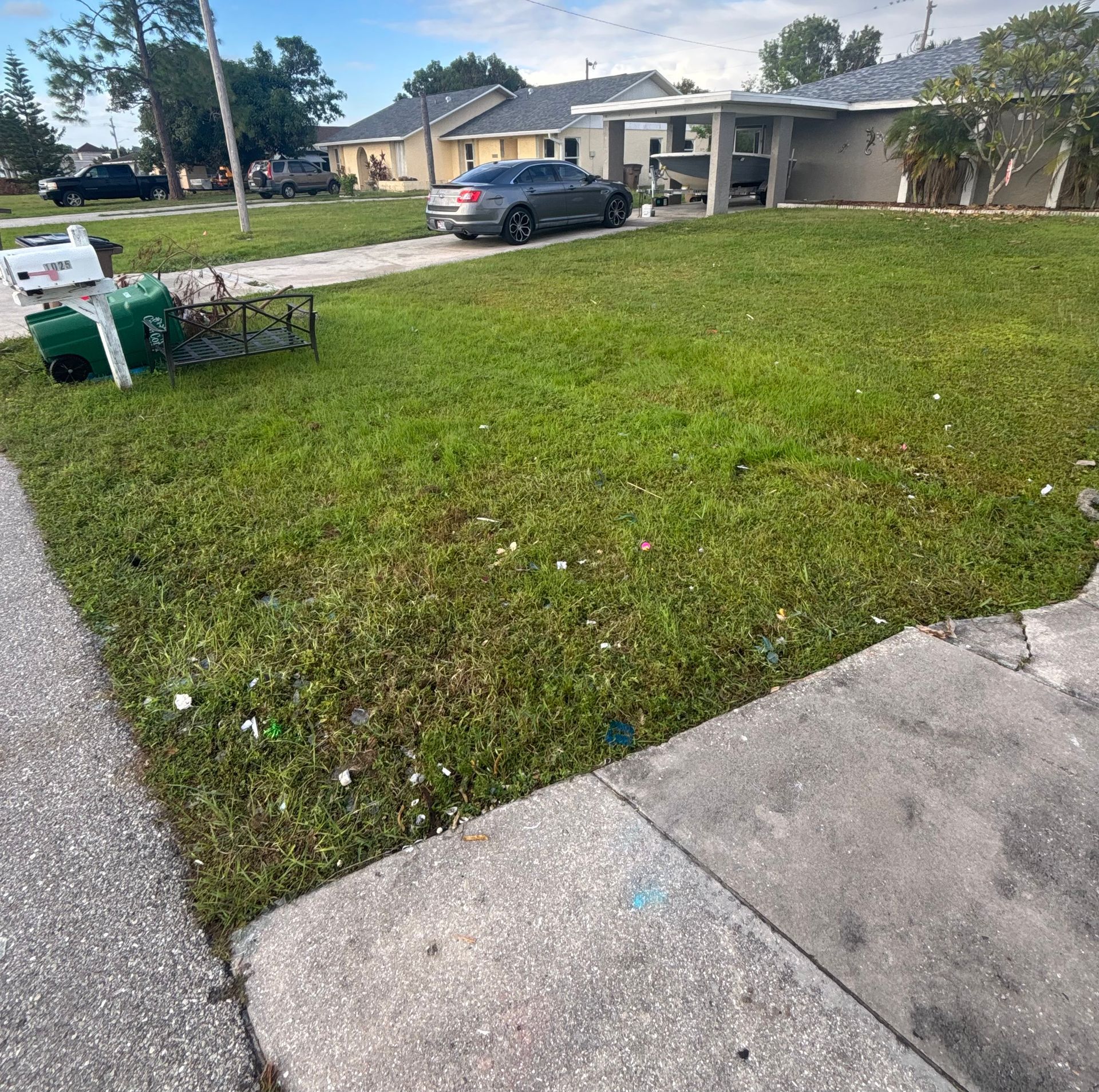 Lawn in front of houses with parked cars, a mailbox, and a sidewalk.