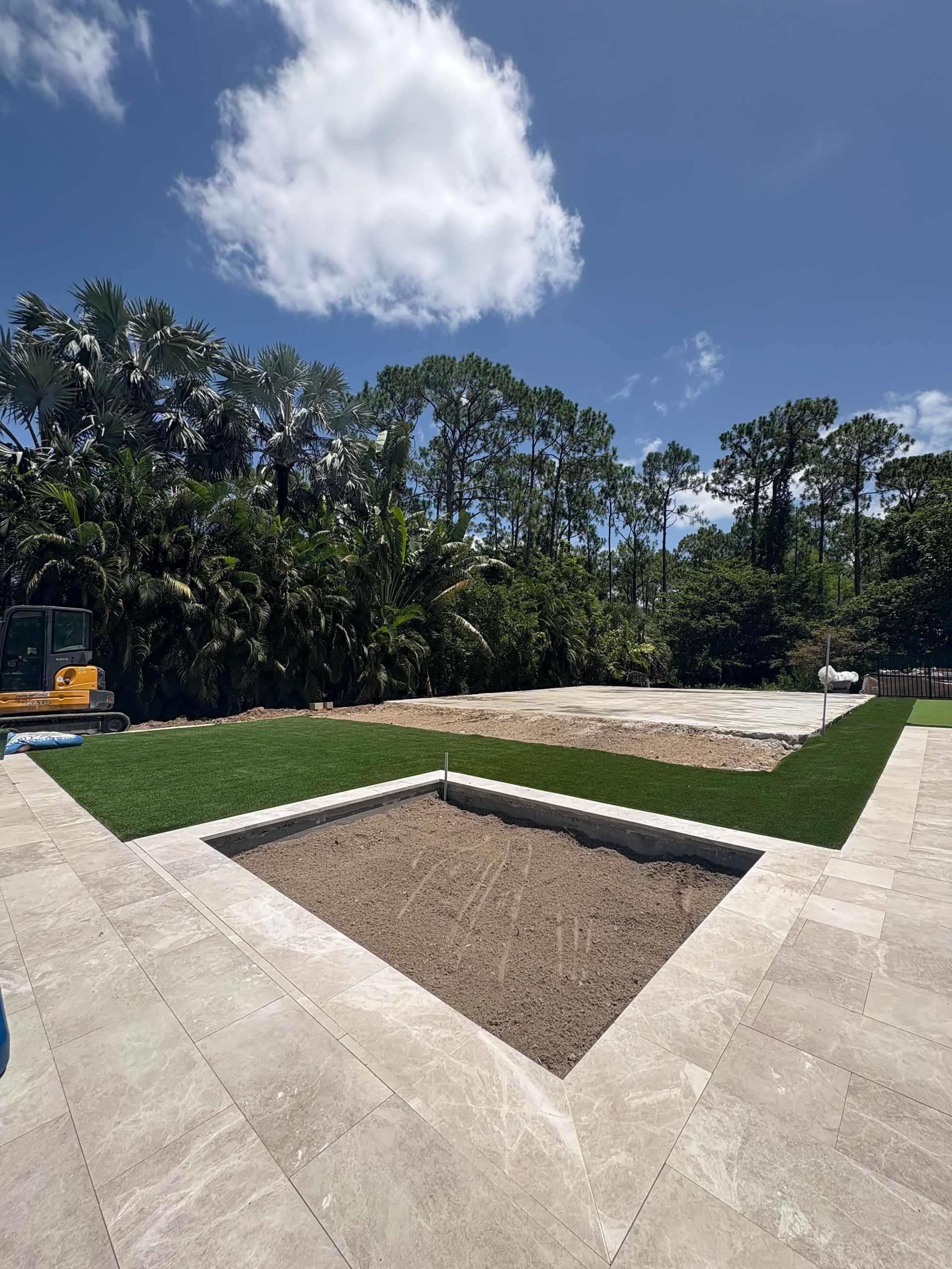 Diamond-shaped garden bed in front of a rectangular grass area, trees, and blue sky.