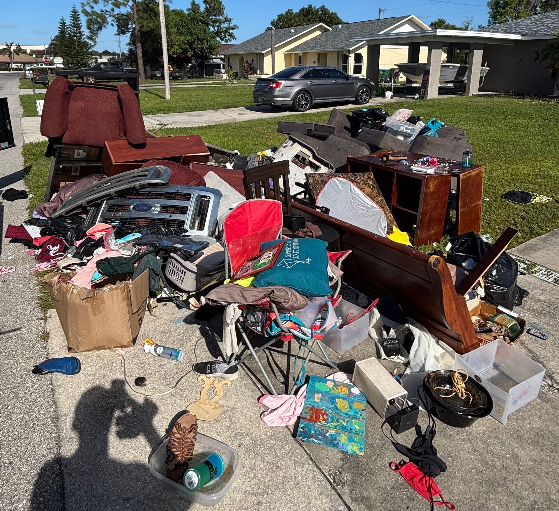Pile of discarded furniture and household items on a sidewalk, possibly for disposal.