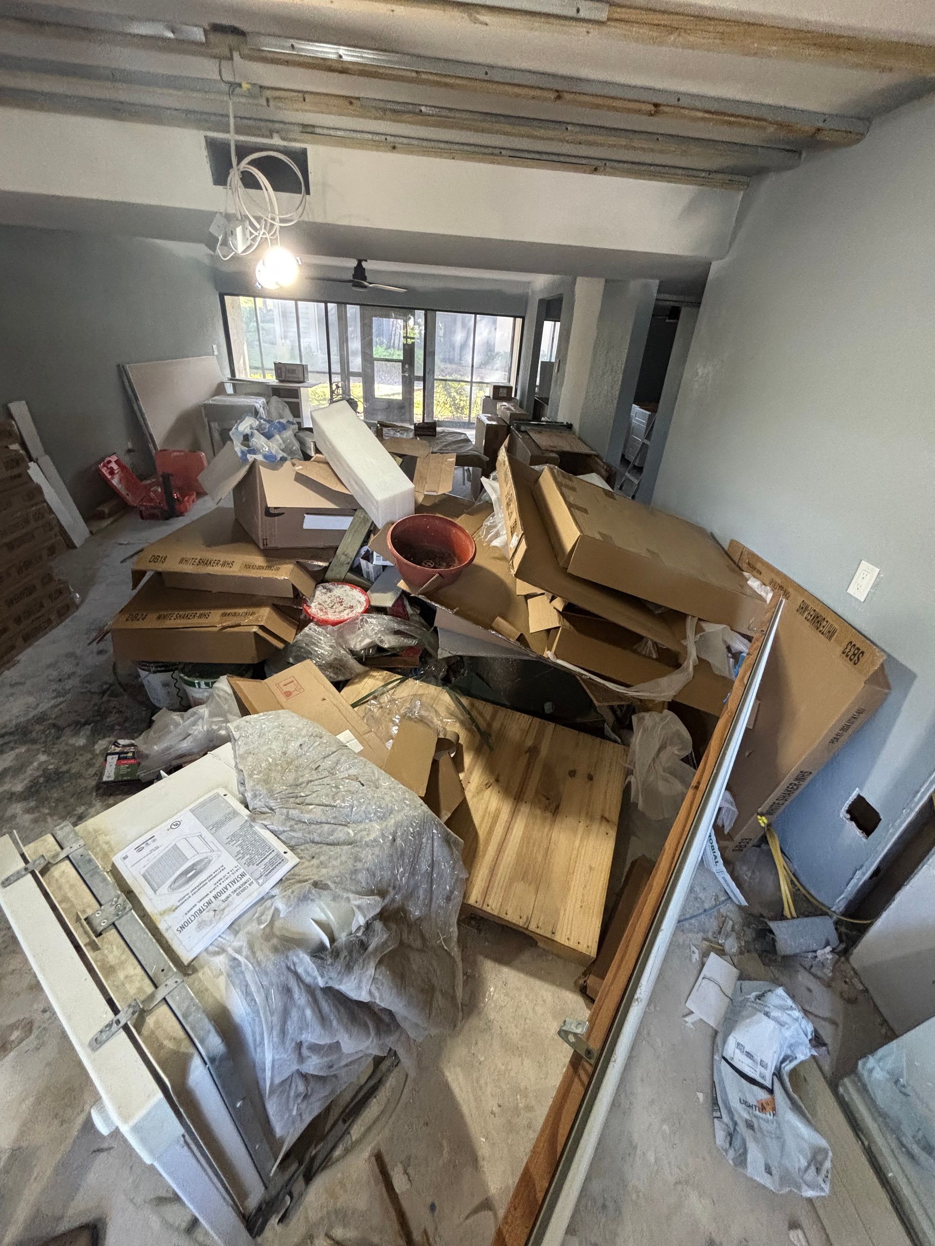 Messy room with construction materials, boxes, and debris.
