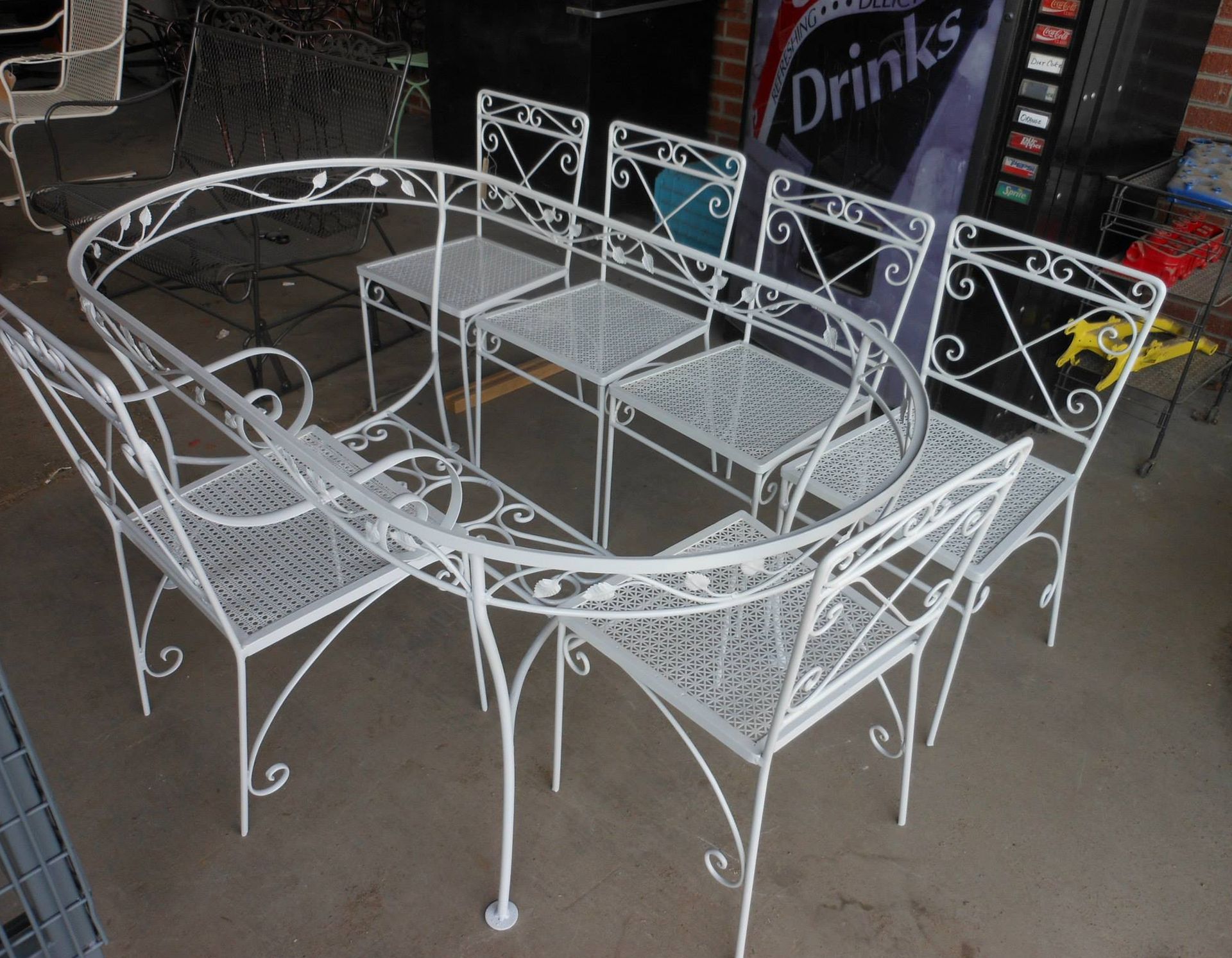 White wrought-iron patio table and four matching chairs displayed indoors.