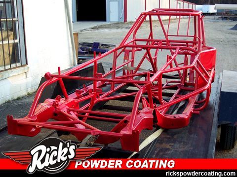 Red race car chassis coated in glossy red, sitting outdoors on pavement with Rick’s Powder Coating watermark