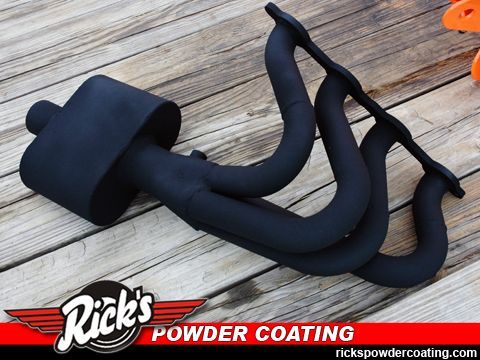 Black powder-coated exhaust headers on a wooden deck with Rick’s Powder Coating logo