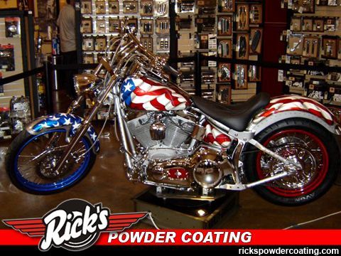Custom chrome motorcycle with red, white, and blue paint in a shop, Rick's Powder Coating logo visible