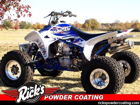 White and blue ATV with Duncan decals on a dirt field, Rick’s Powder Coating logo at bottom left