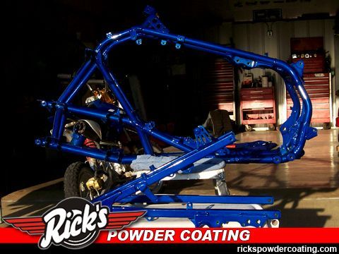 Blue powder-coated vehicle frame in a workshop with Rick’s Powder Coating logo in the corner