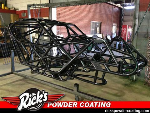 Black race car chassis frame in a workshop, coated in glossy black powder.
