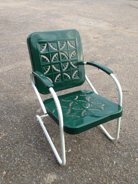 Green metal patio chair with silver frame on a pavement surface