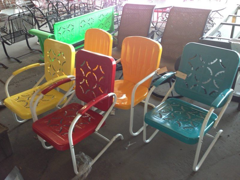 Colorful metal patio chairs arranged outdoors on a concrete floor.