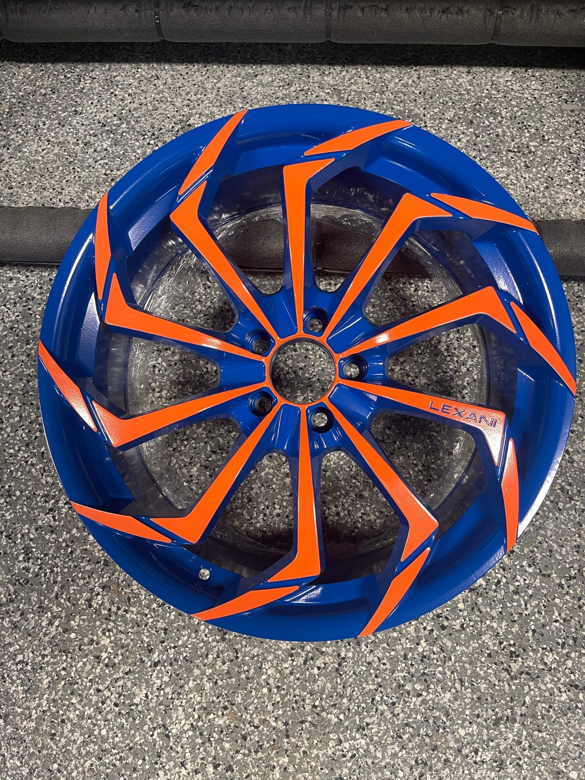 Blue and orange spiral wheel cover on a gray textured surface
