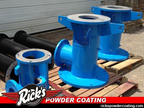 Blue industrial powder-coated metal parts on wooden pallets outdoors, with Rick’s Powder Coating watermark