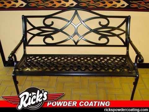 Black wrought-iron bench with decorative backrest and lattice seat on a tiled floor